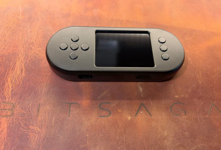 The black SeedSigner+ Premium lying at an angle, screen off, with the four-way pad on the left, three buttons on the right and the USB-C power port on its lower edge