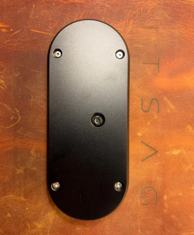 The back of the black SeedSigner+ Premium, a flat aluminium plate held by four corner screws with the camera lens in the middle