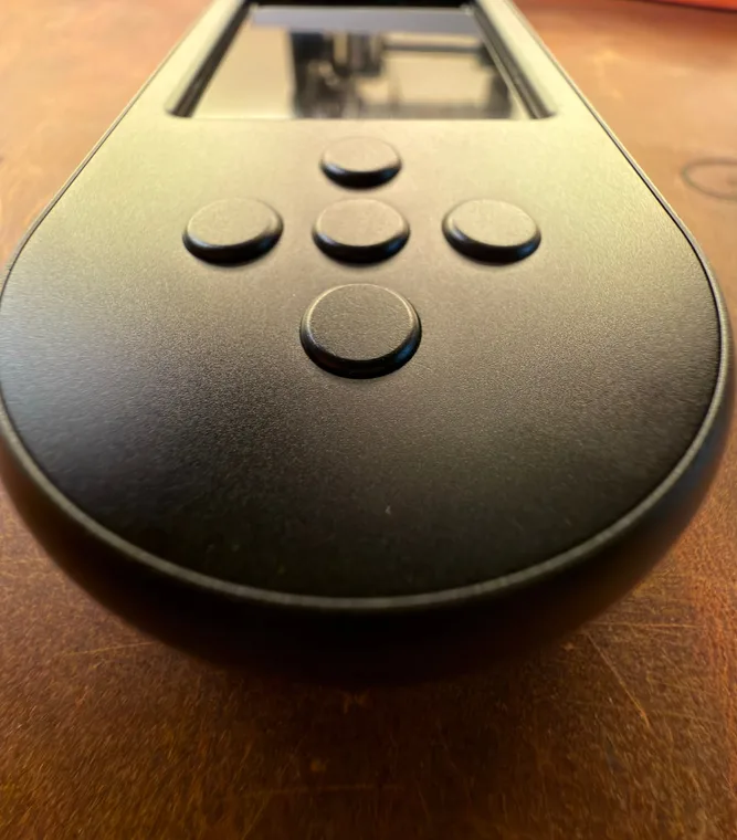 Close-up of the black SeedSigner+ Premium's controls, four round direction buttons around a larger select button, with the camera opening in the top edge